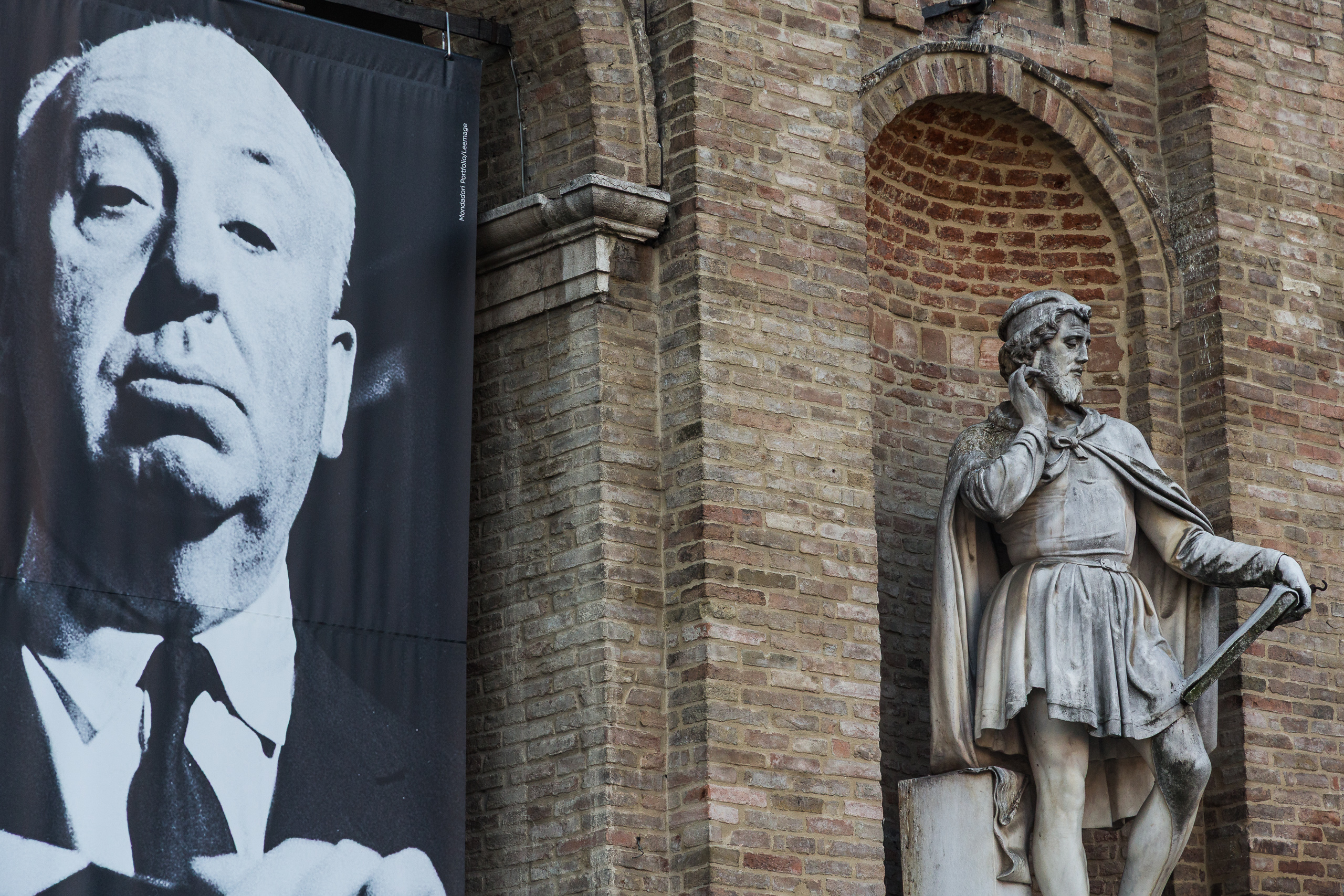 Hitchcock-Ausstellung neben einer Statue an der Backsteinwand