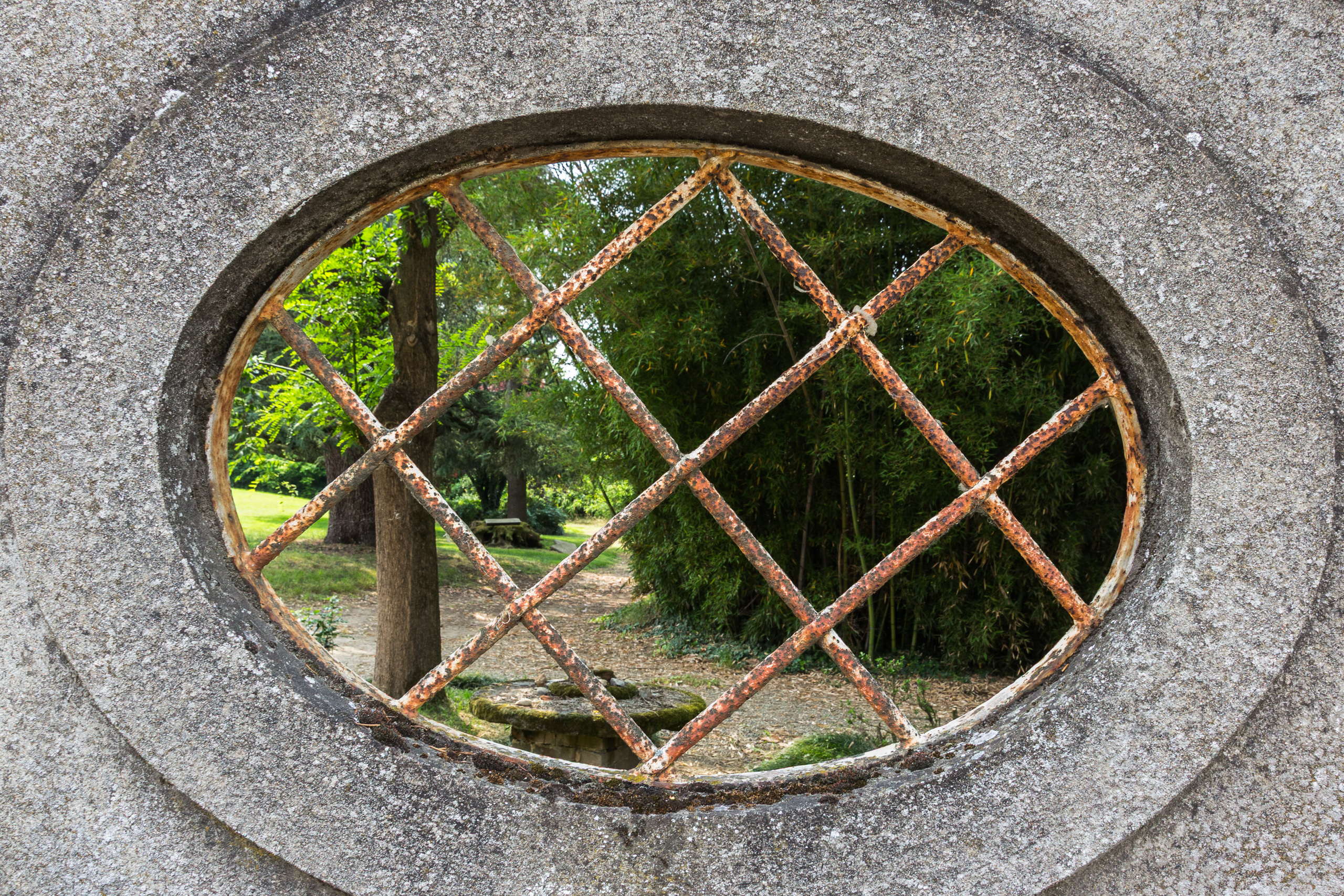 Blick durch ein altes Ovalfenster in einen Park