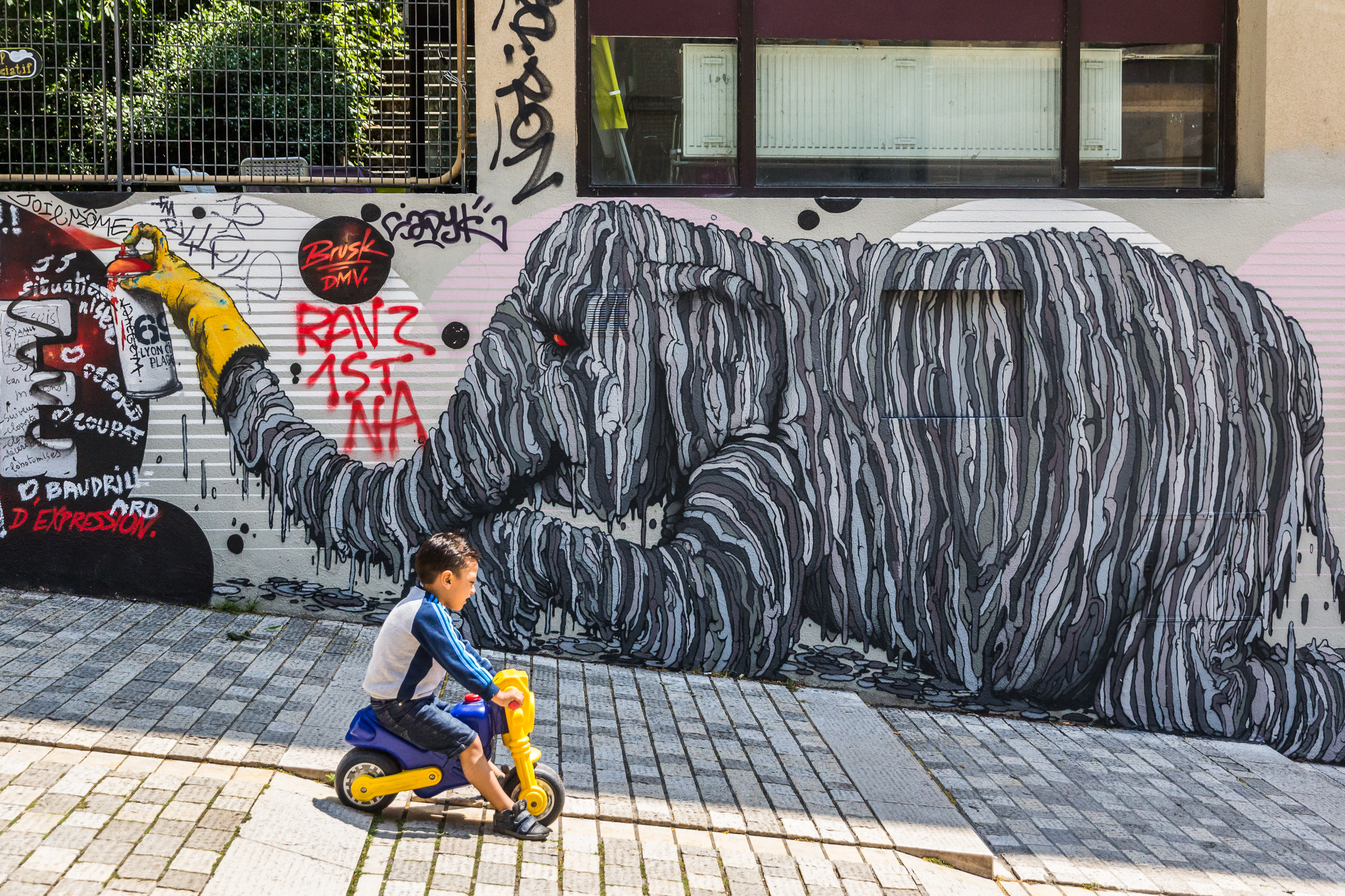 Street-Art in Lyon – ein Kind radelt am Wandbild vorbei