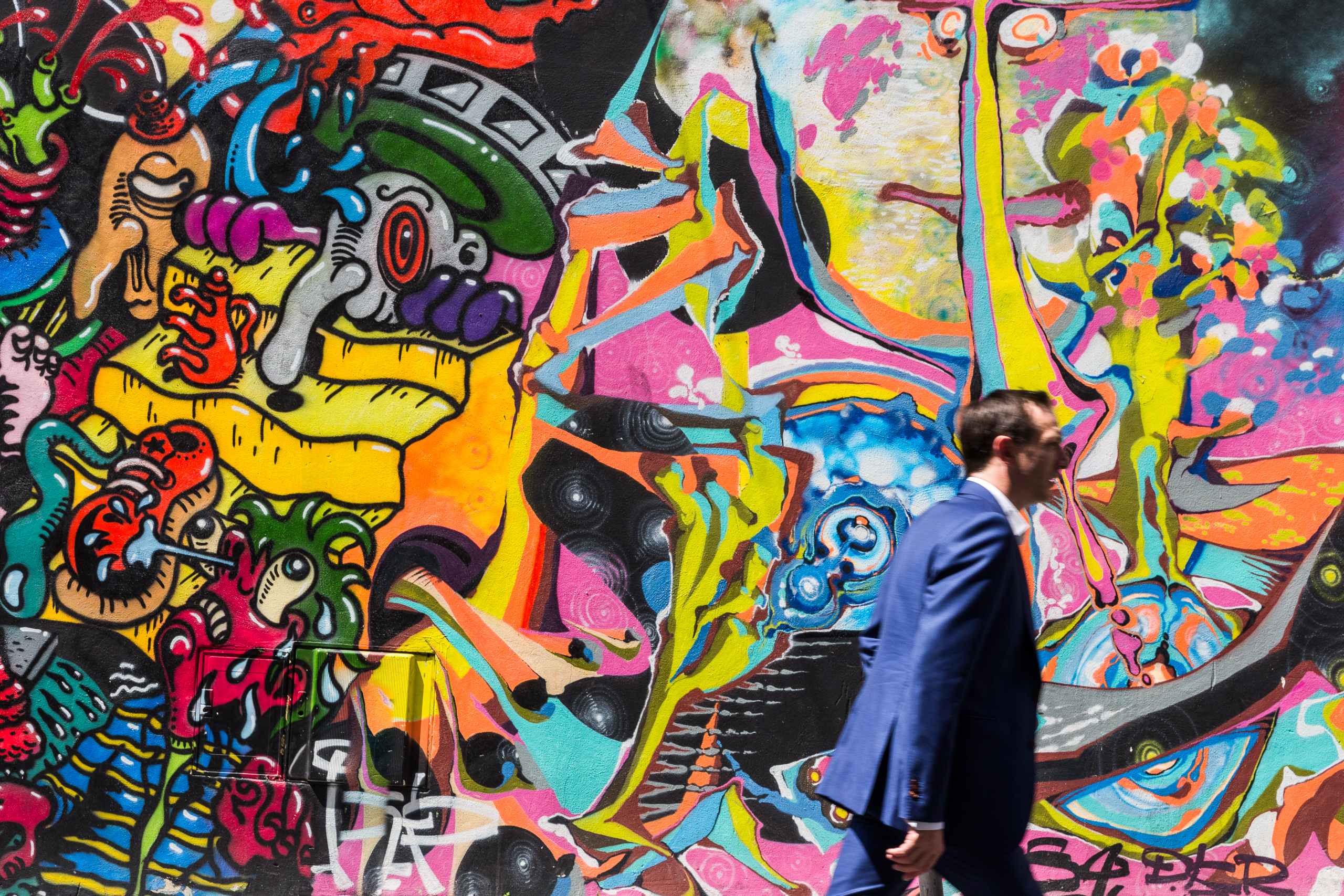 Mann im Anzug vor einer bunten Graffiti-Wand