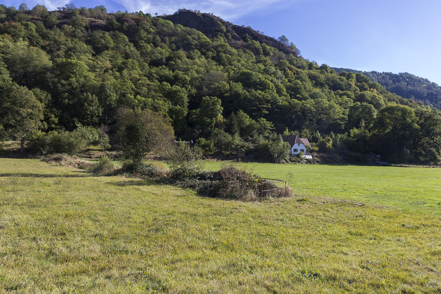 Industrieruinen mit hohen gemauerten Schloten im engen Tal